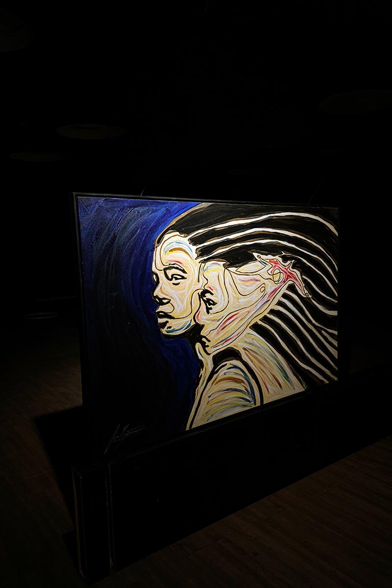 Dual portrait painting by Juca Máximo showcased under dramatic lighting — contemporary art installation exploring emotional identity.