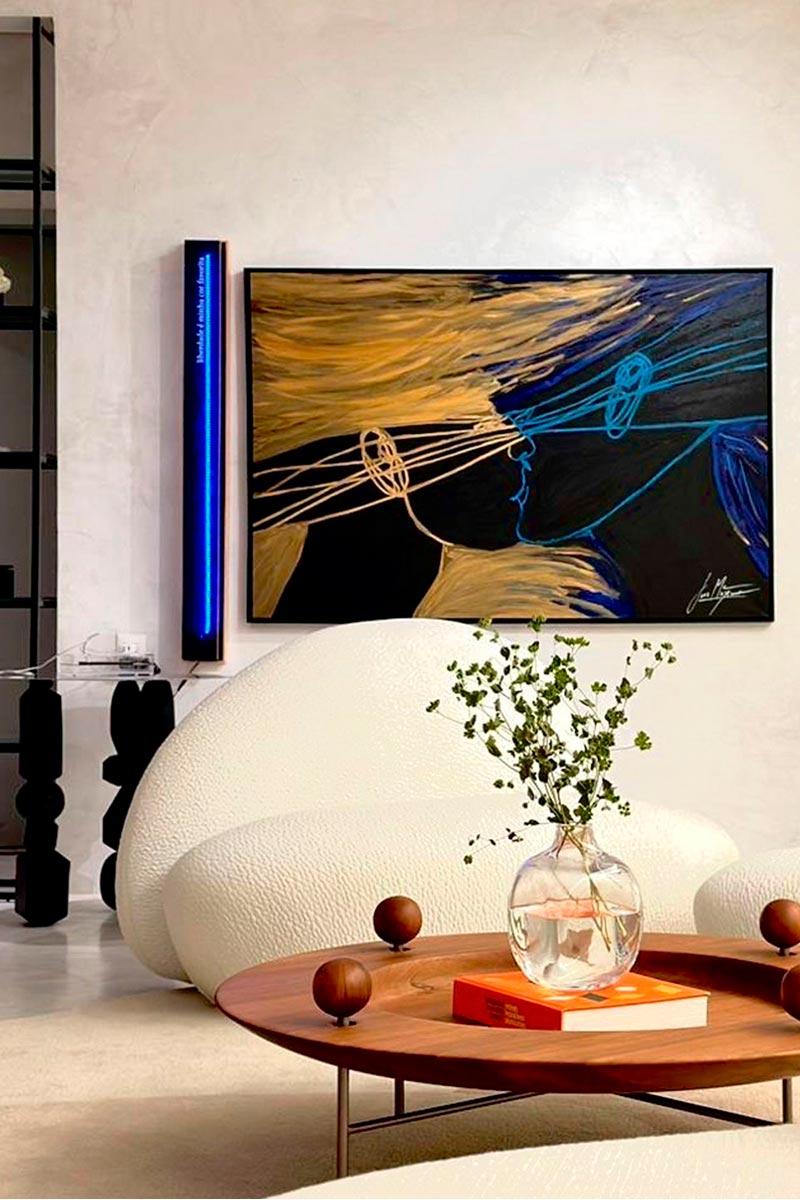 Contemporary living room featuring a painting from Juca Máximo’s Gravity series — expressive golden and blue profiles exchanging energy in an elegant interior.