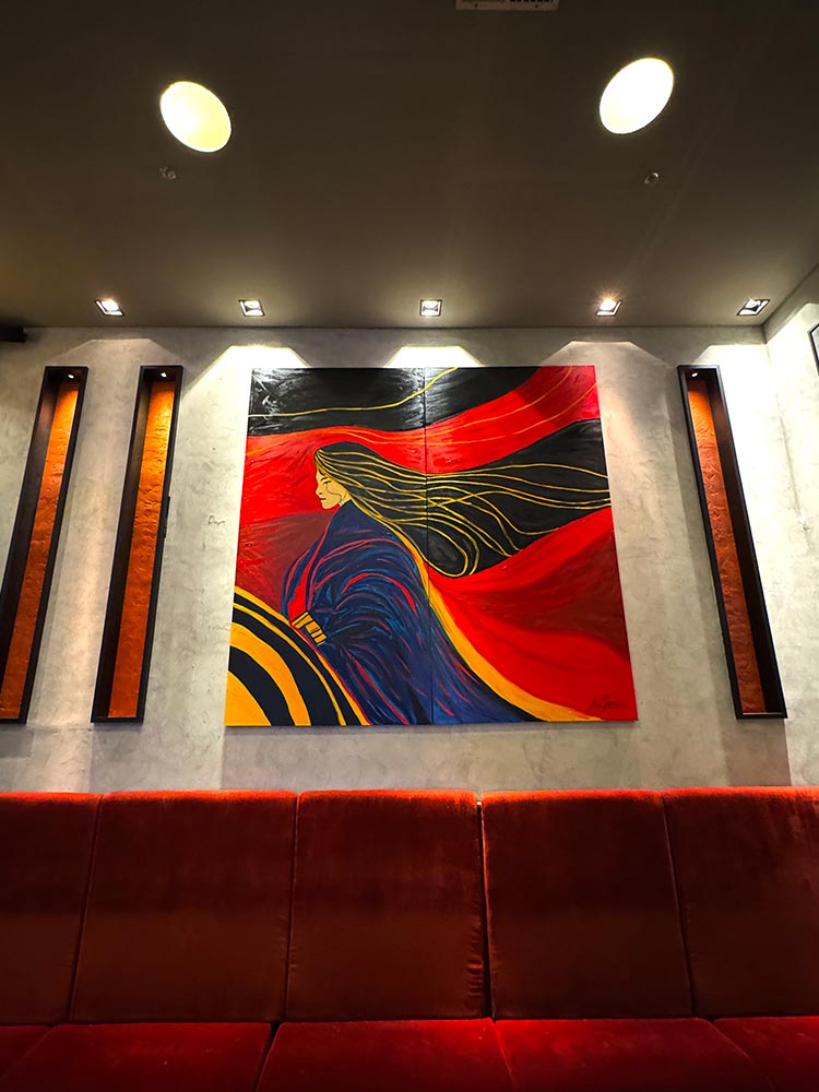 Colorful contemporary painting by Juca Máximo on display in a modern interior, evoking feminine strength with bold strokes and flowing lines.