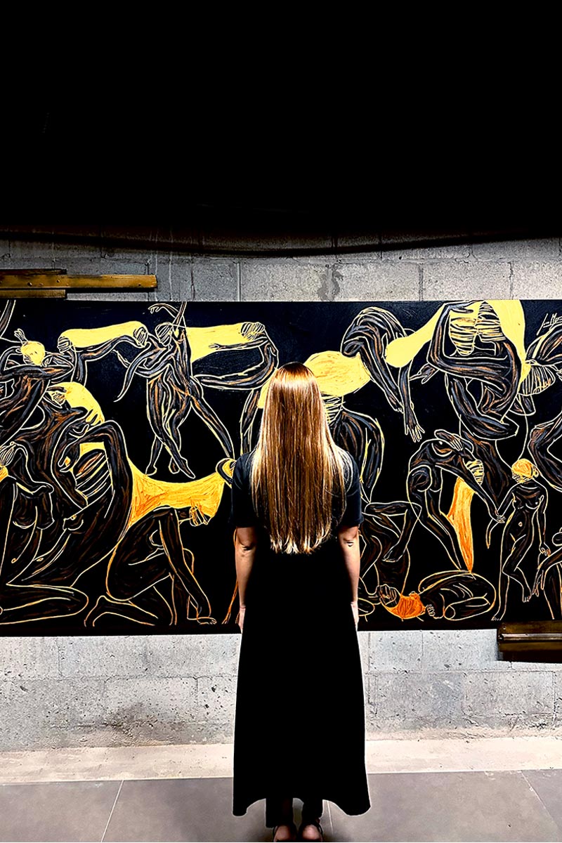 Back view of a woman admiring Juca Máximo’s large-scale canvas from the Energy Series — a powerful expression of collective movement and emotional resonance.