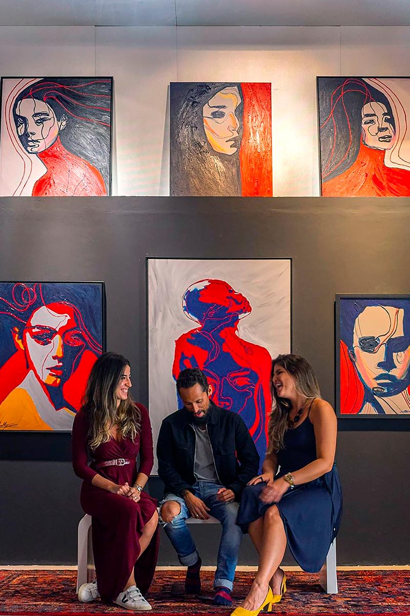 Group admiring Juca Maximo’s expressive Portrait Colors series during an exhibition – emotional intensity through bold lines and color.