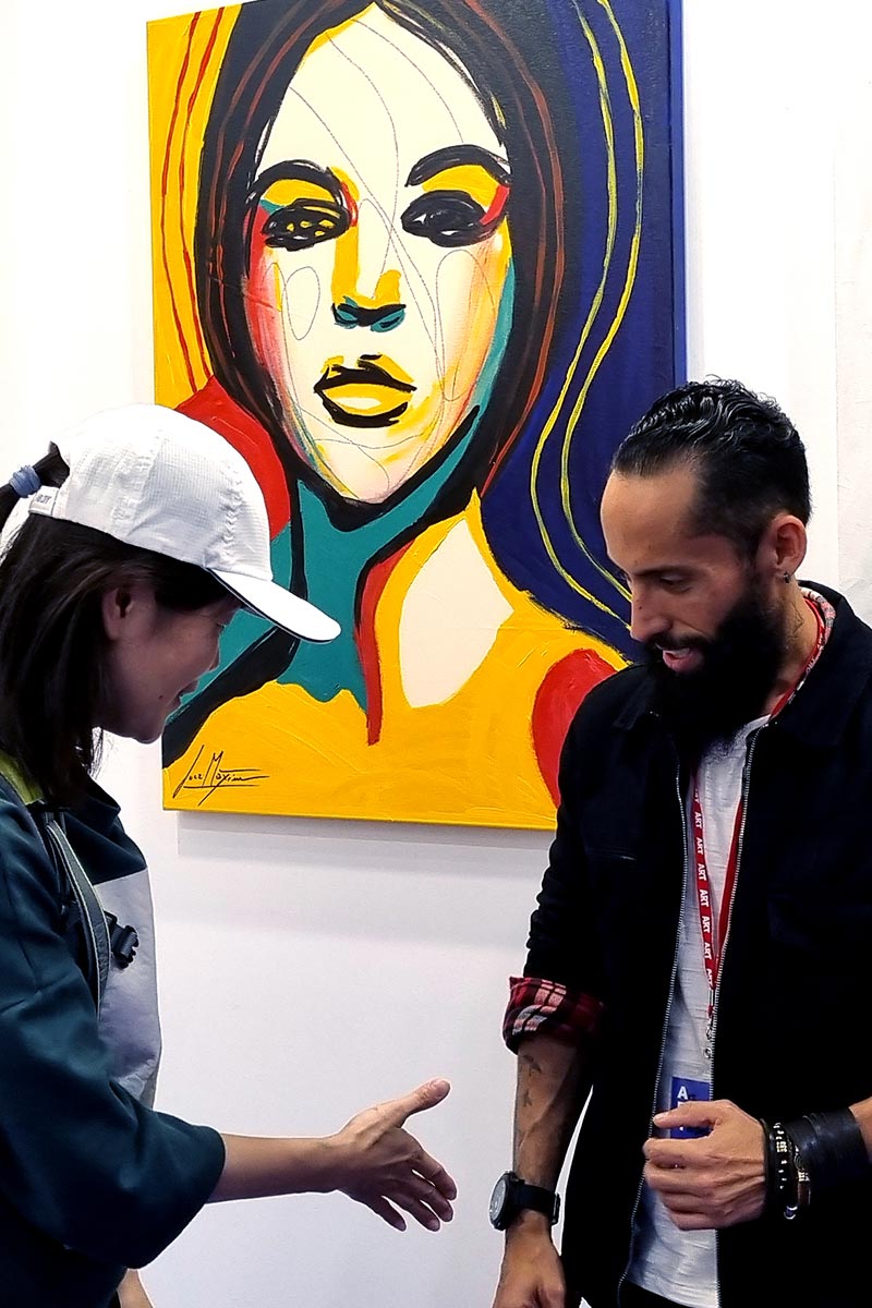 Public interaction at an international exhibition in Taipei featuring a colorful portrait by Brazilian artist Juca Máximo, part of the acclaimed Retails series.