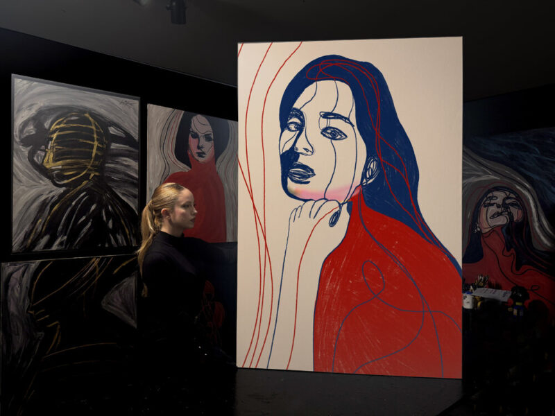 juca-maximo-portrait_colors-XVIII-wideview Portrait Colors XVIII – She Holds Her Own Voice. A minimalist feminine portrait drawn with expressive blue and red lines. The face shows quiet introspection while fluid contours overlap the figure, suggesting emotion, memory, and inner voice. Clean background enhances the contrast and the conceptual style.