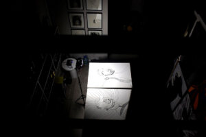 Contemporary artist studio with large canvas drawings in black ink on table, overhead view of artwork in progress, Traces series by Brazilian artist Juca Máximo