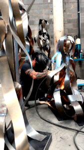Juca Máximo welding a contemporary steel sculpture in his studio. / Juca Máximo soldando uma escultura contemporânea em aço no ateliê.